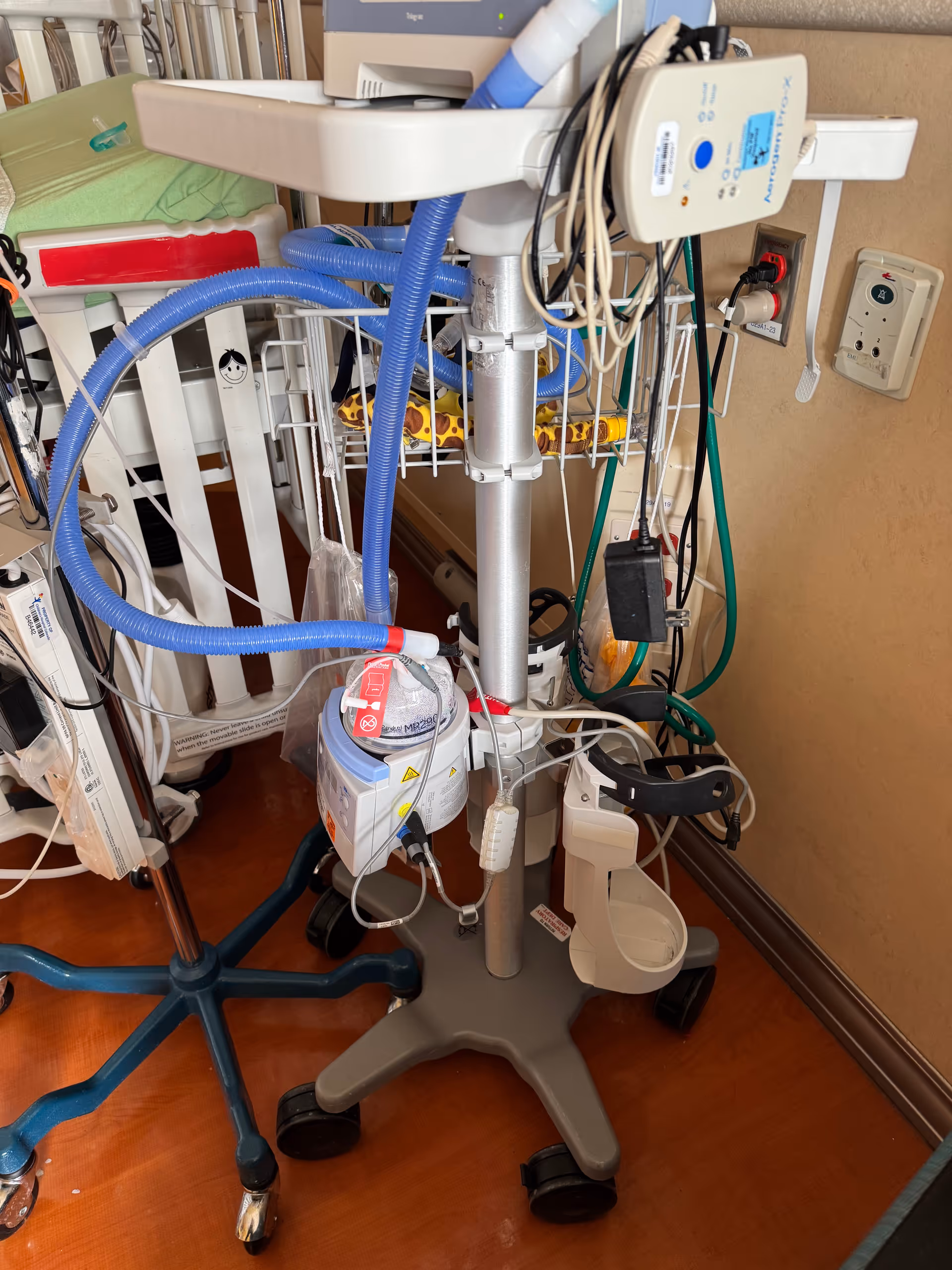 Medical equipment and an IV pole clutter a hospital-style senior care room.