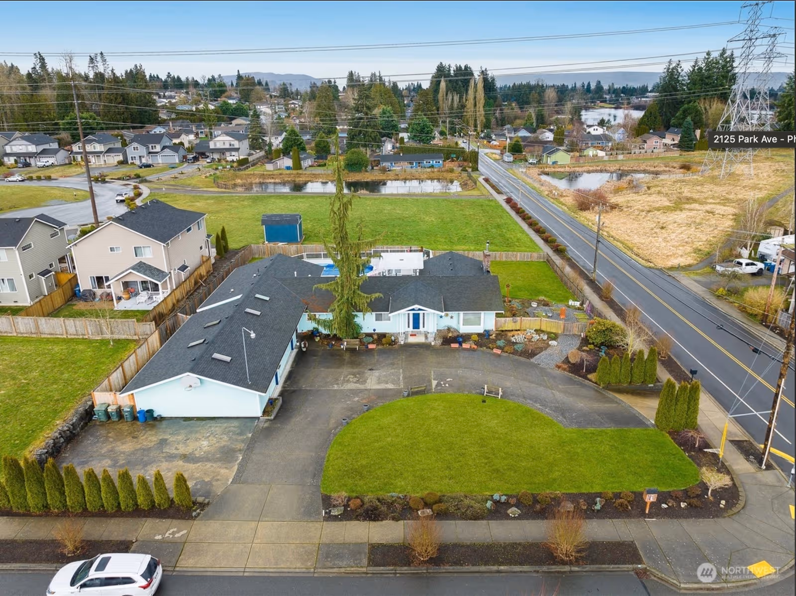 Aerial view of a single-story home with curved driveway and green lawn.