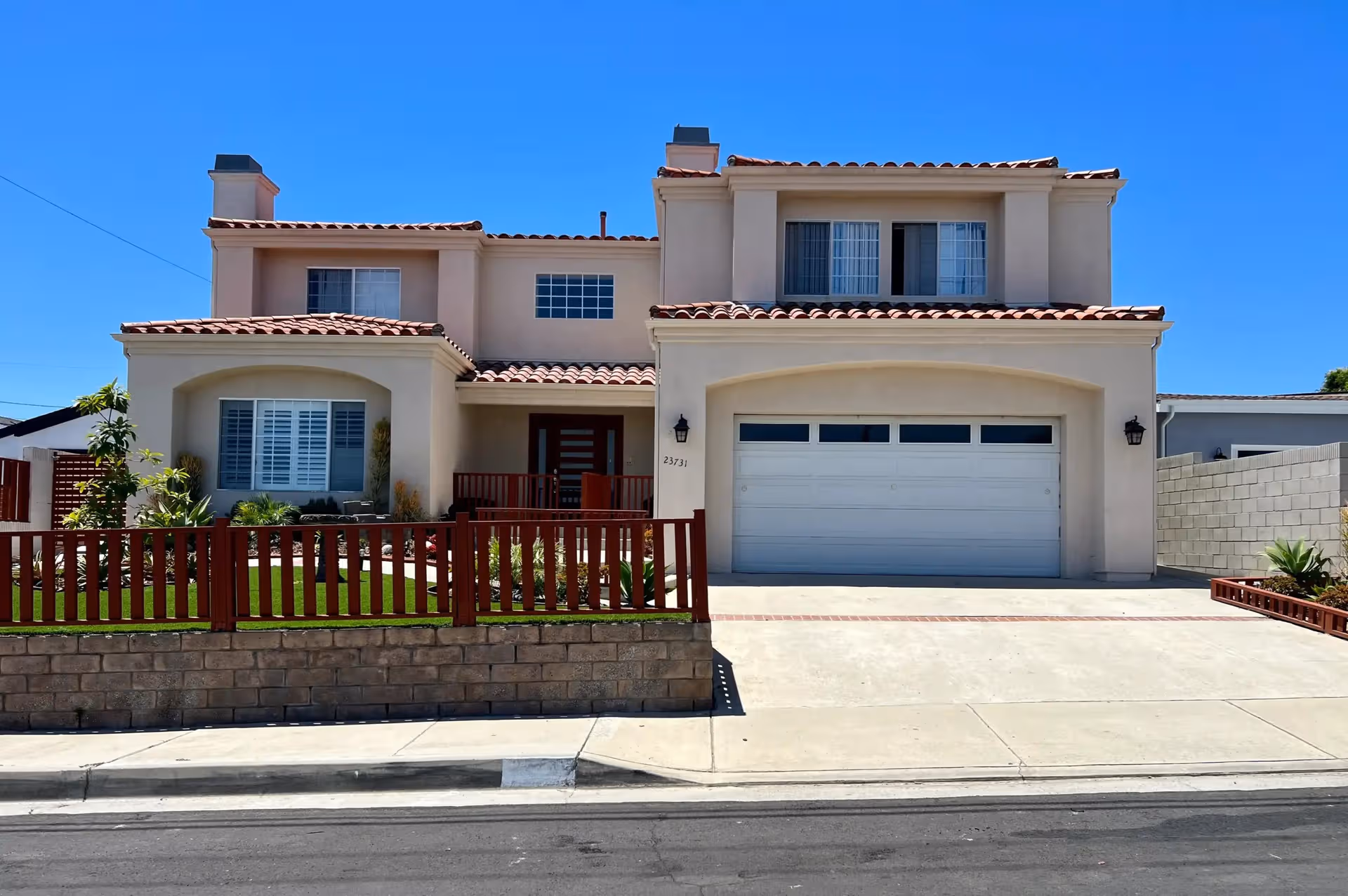 Two-story beige senior living facility with a gated front yard and garage.
