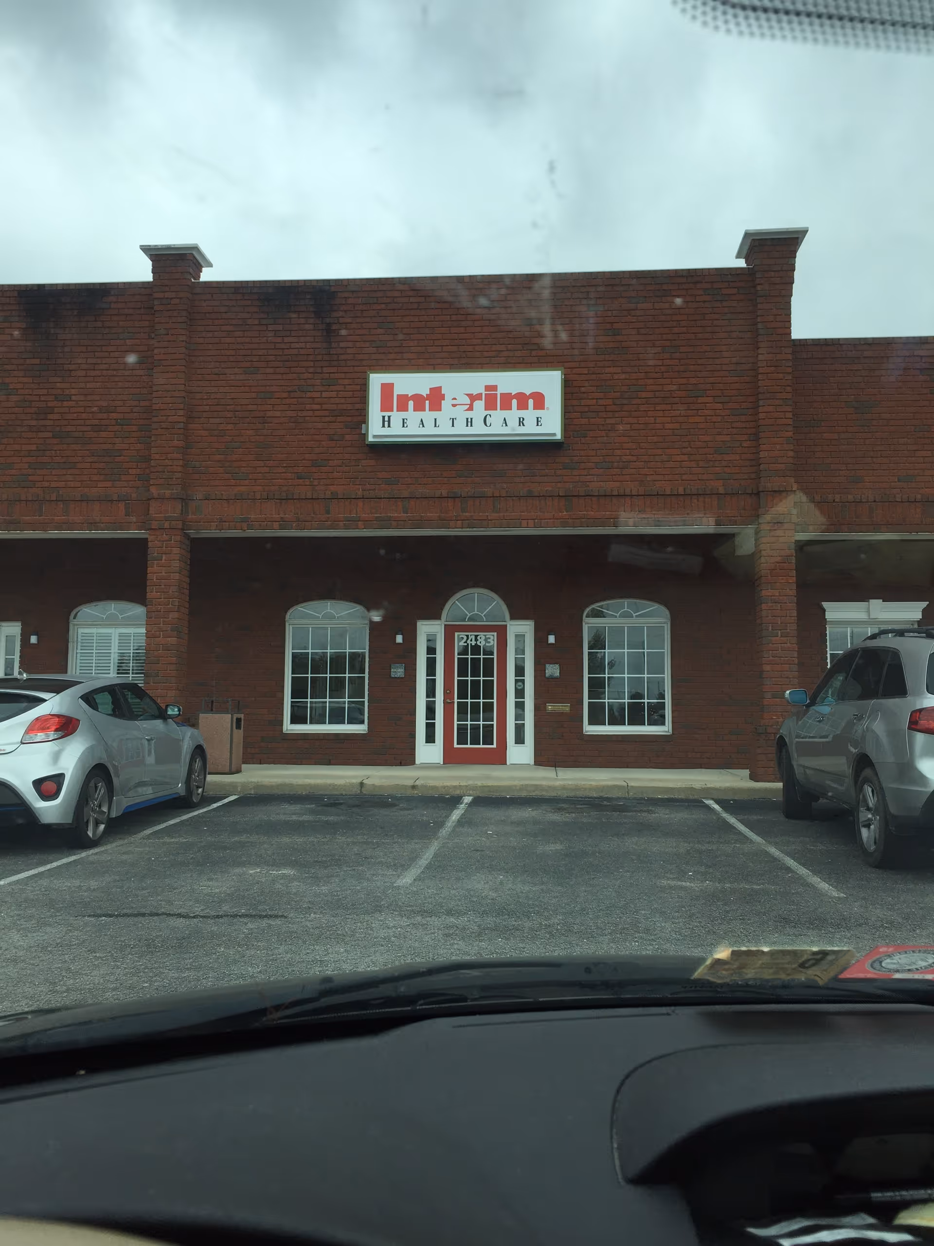 Brick facility exterior with Interim HealthCare sign and glass entrance doors.
