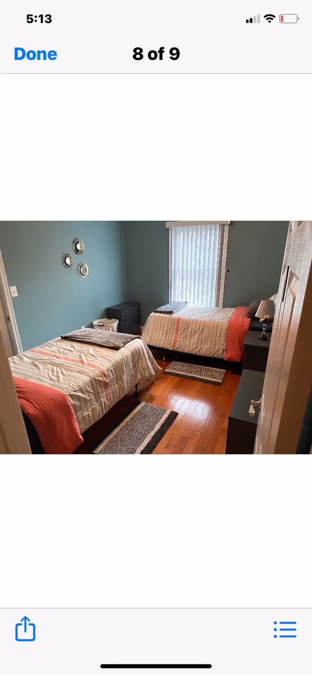 Two twin beds in a teal-walled bedroom with nightstands and rugs.