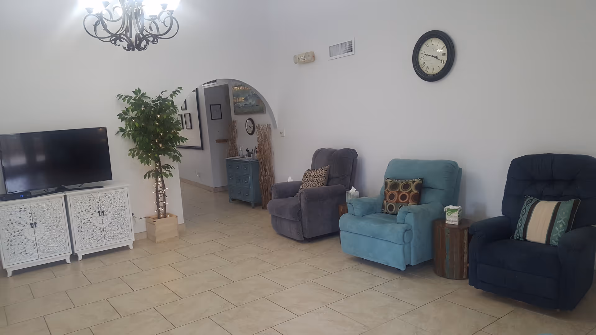 A bright modern living room in a senior facility with recliners, TV, and decor.