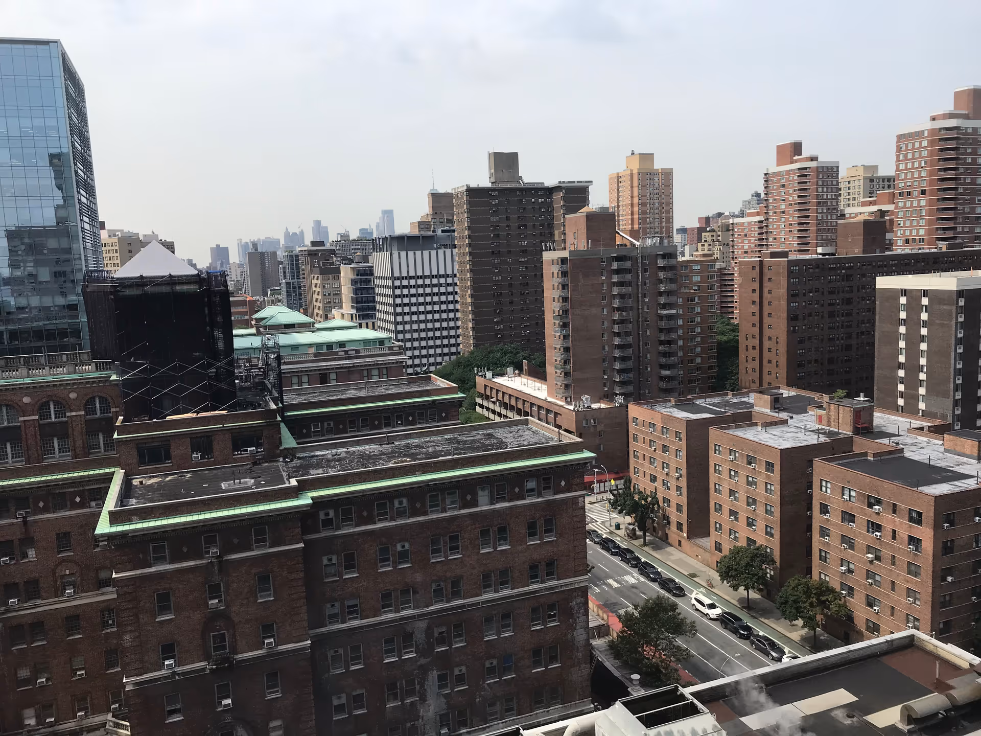 City skyline with brick apartment buildings and rooftops seen from a high-rise vantage.