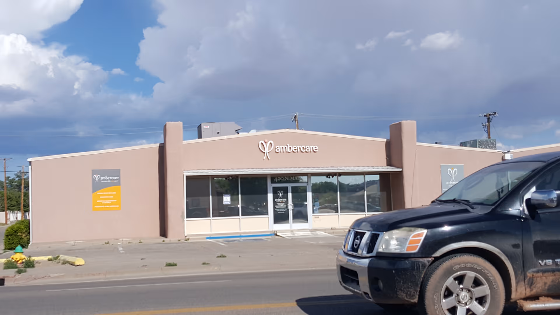 Front view of Ambercare senior living building with a parked black SUV.