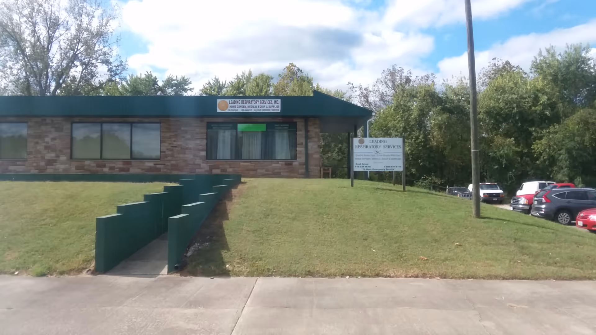 Front view of a brick building with green awning and Leading Respiratory Services sign.