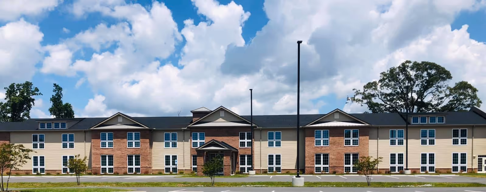 Long brick-and-beige senior living building with multiple windows and a central entrance.