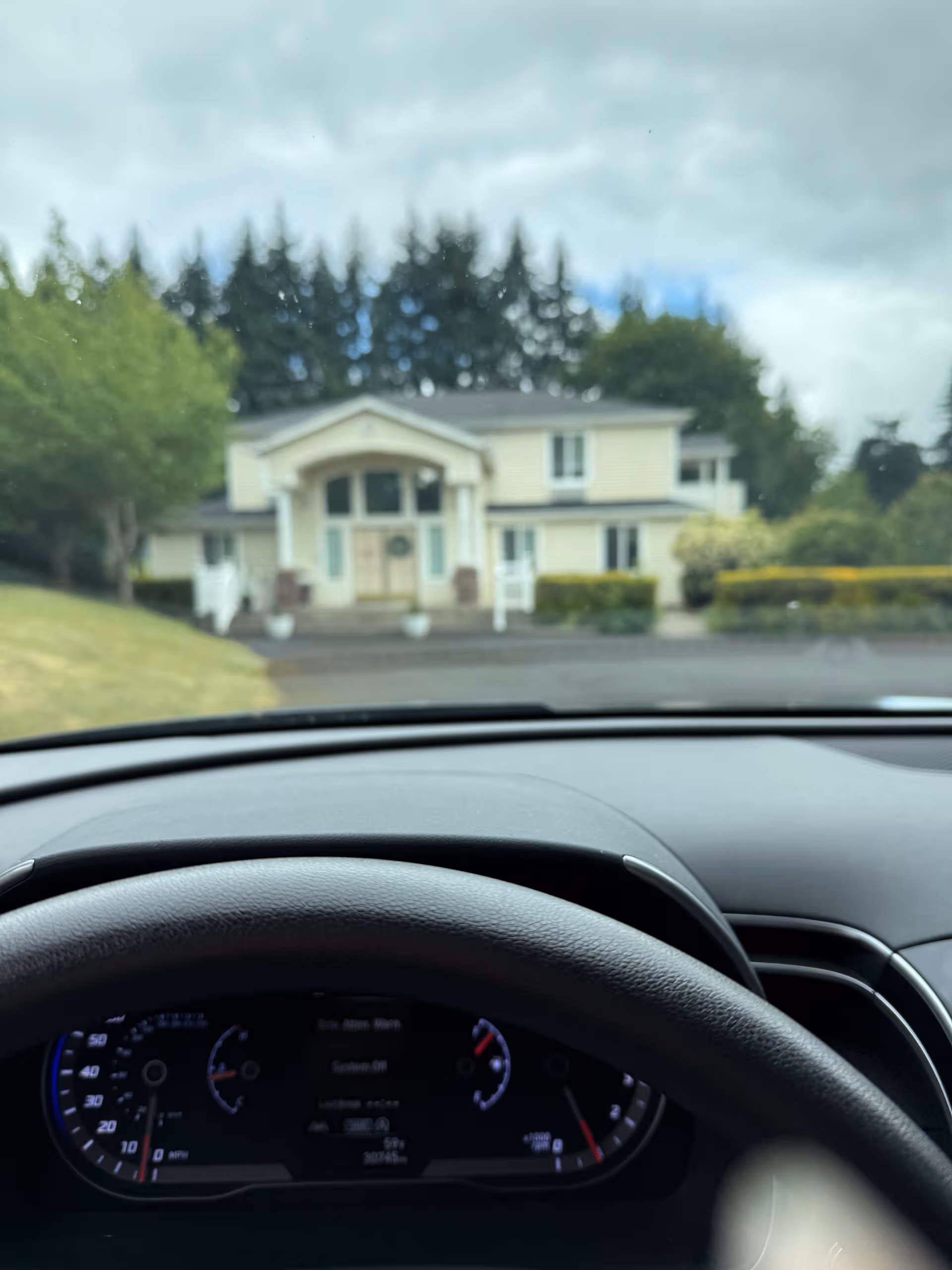From inside a car, the light-colored building front of a senior care facility is visible.