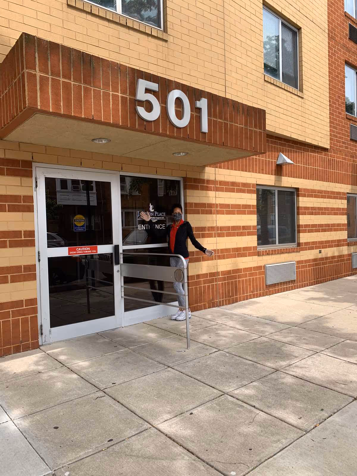 Person stands at glass entrance of brick building labeled 501.