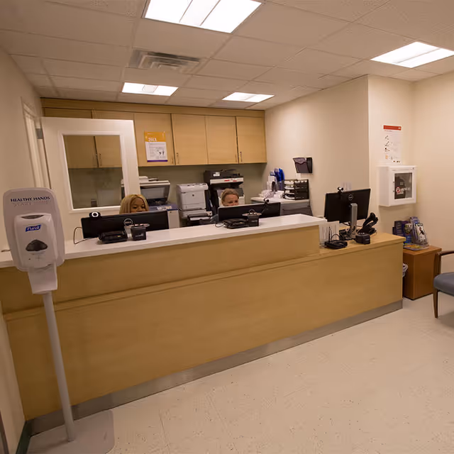 Reception desk with two staff at work in NYU Langone Brooklyn Medical Arts Pavilion.