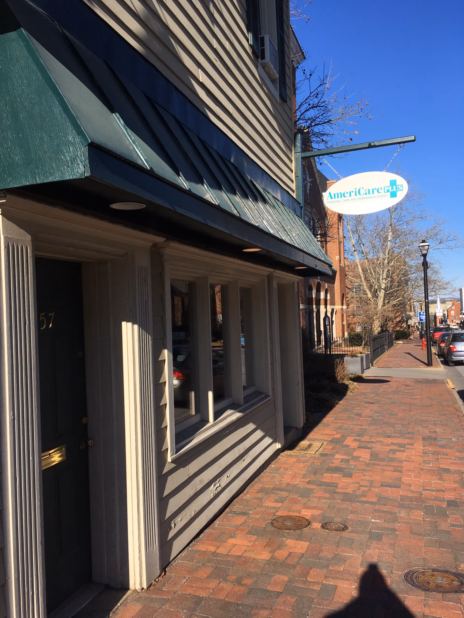 Exterior street view of AmeriCare Plus Home Care storefront with sidewalk and sign.