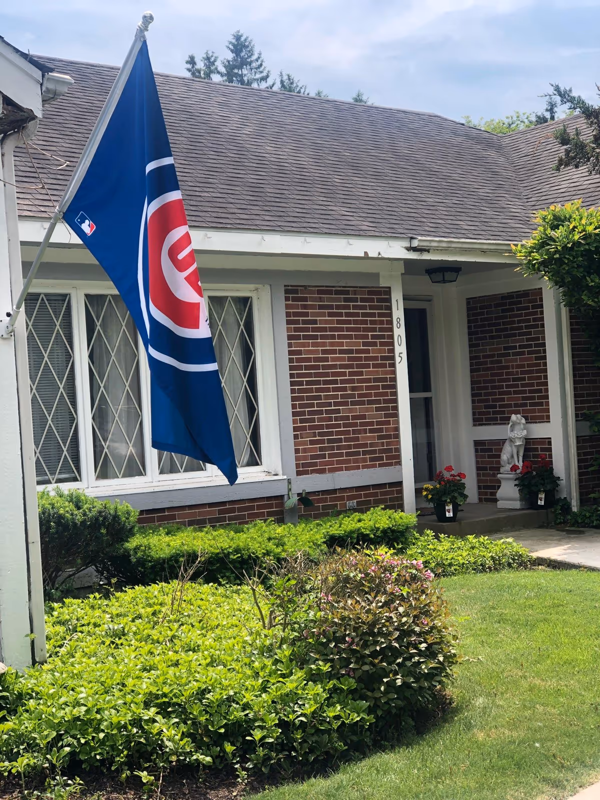 Brick building front with flag, shrubs, and a welcoming entrance.