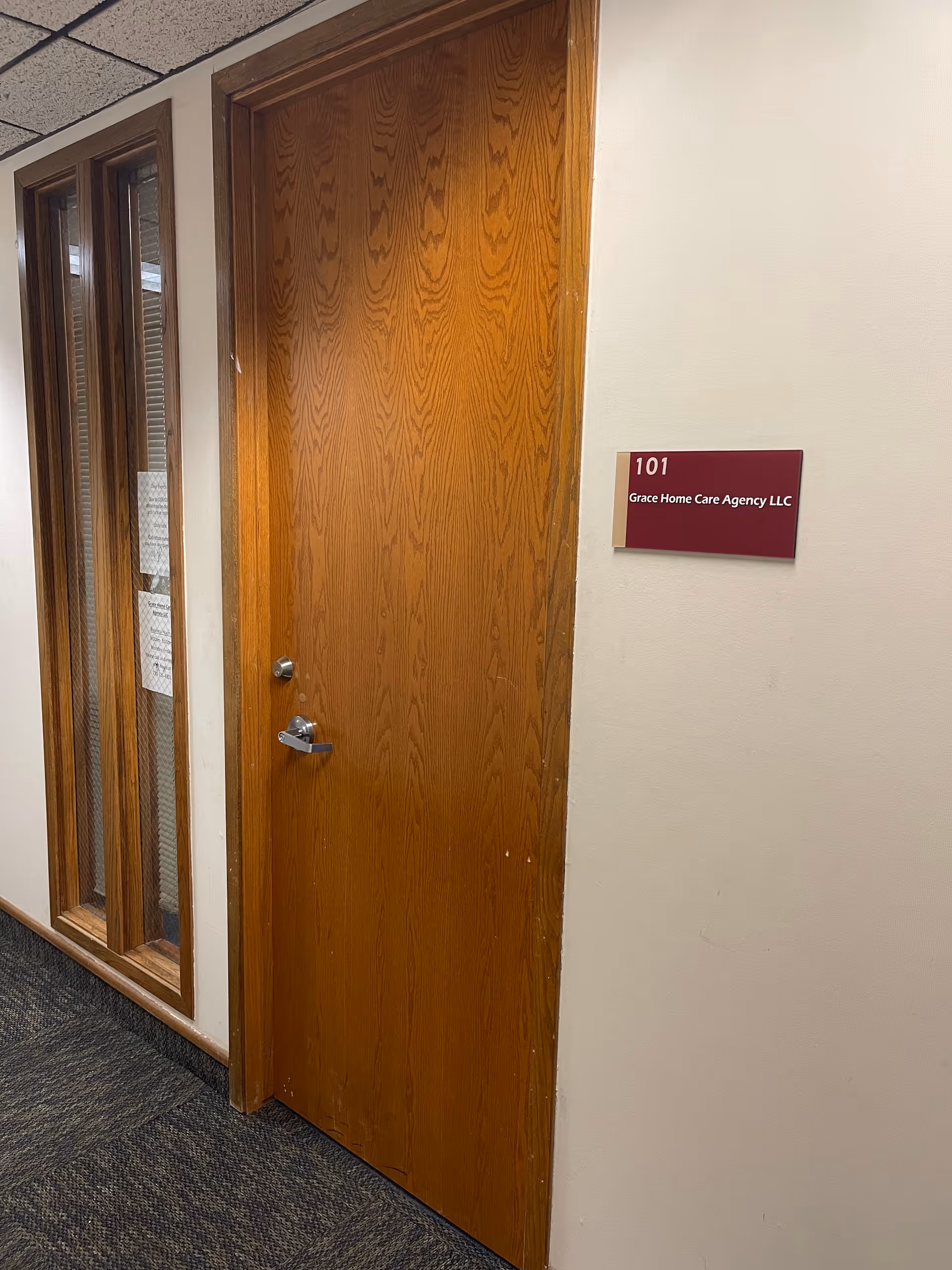 Wooden interior door in hallway with Grace Home Care Agency LLC sign on wall.