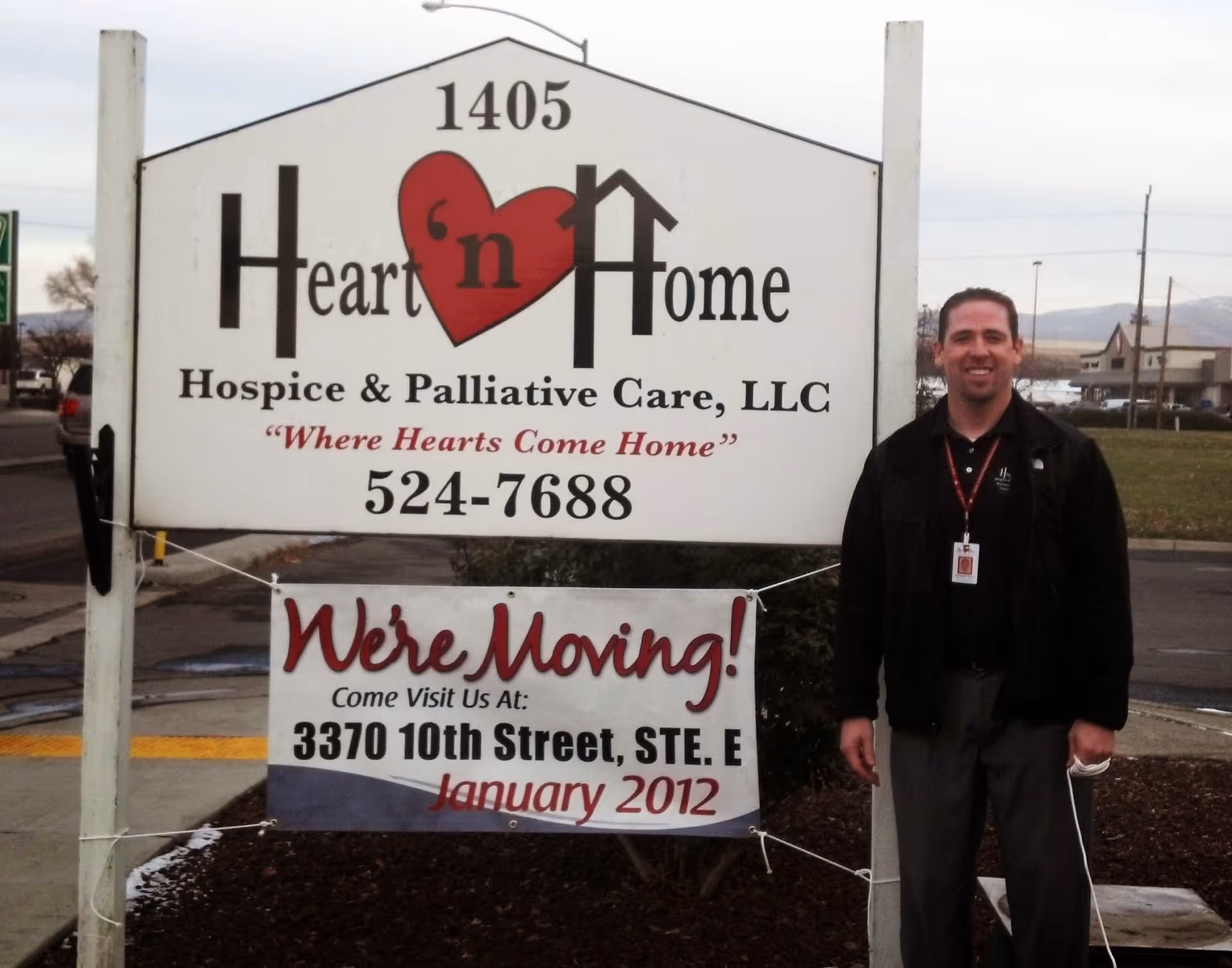 A man stands beside a Heart 'n Home Hospice sign outside the facility