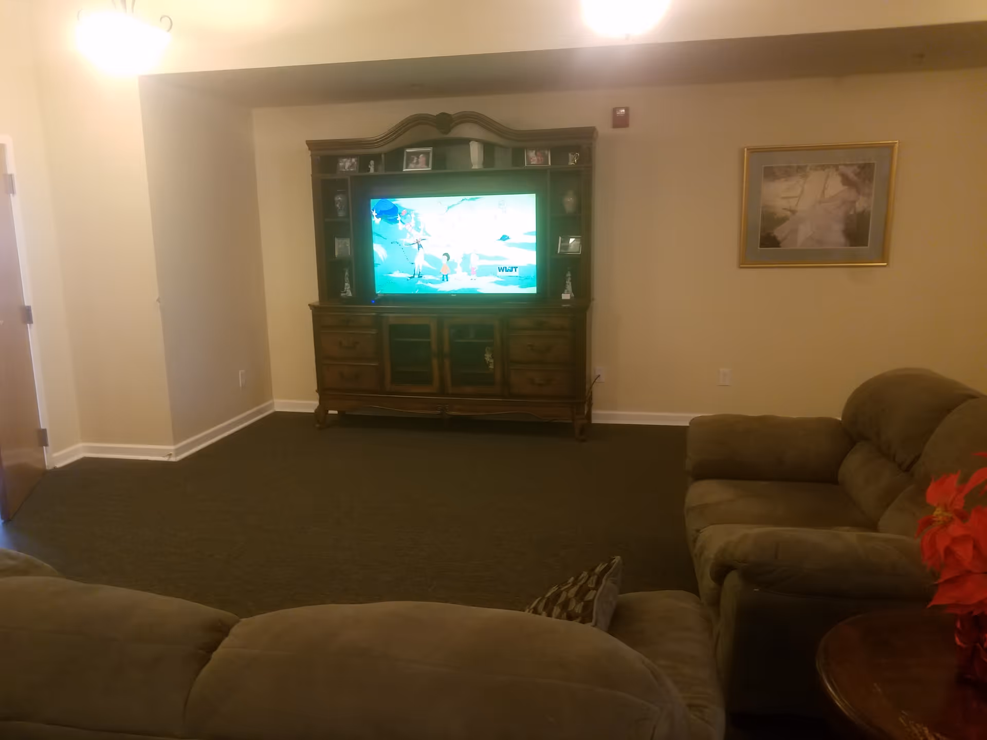 Cozy living room with brown sofas facing a large TV and entertainment cabinet.