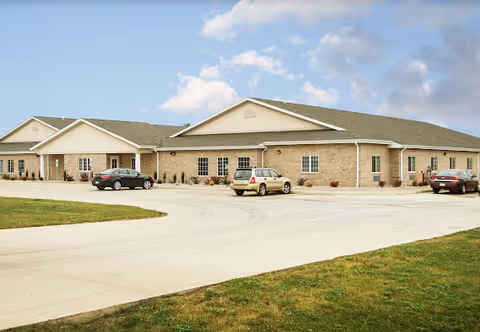Single-story brick senior living facility with a curved driveway, parking lot, and green lawn.