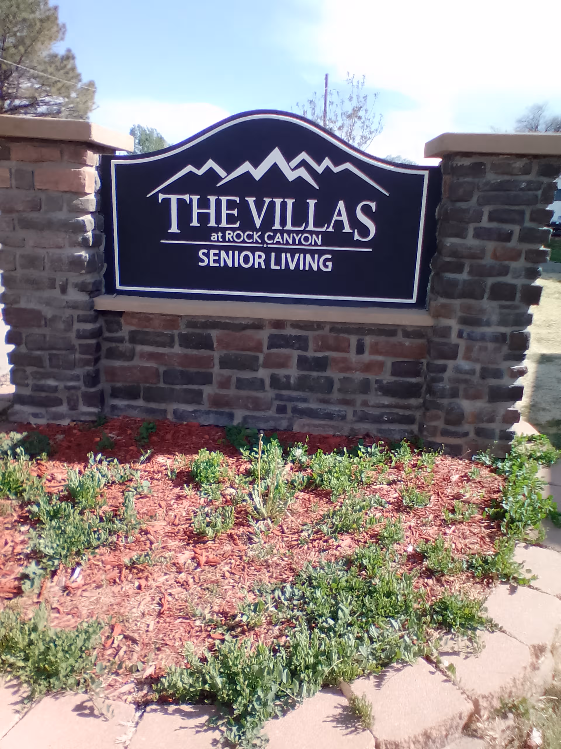 Sign for The Villas at Rock Canyon Senior Living on a stone entrance wall