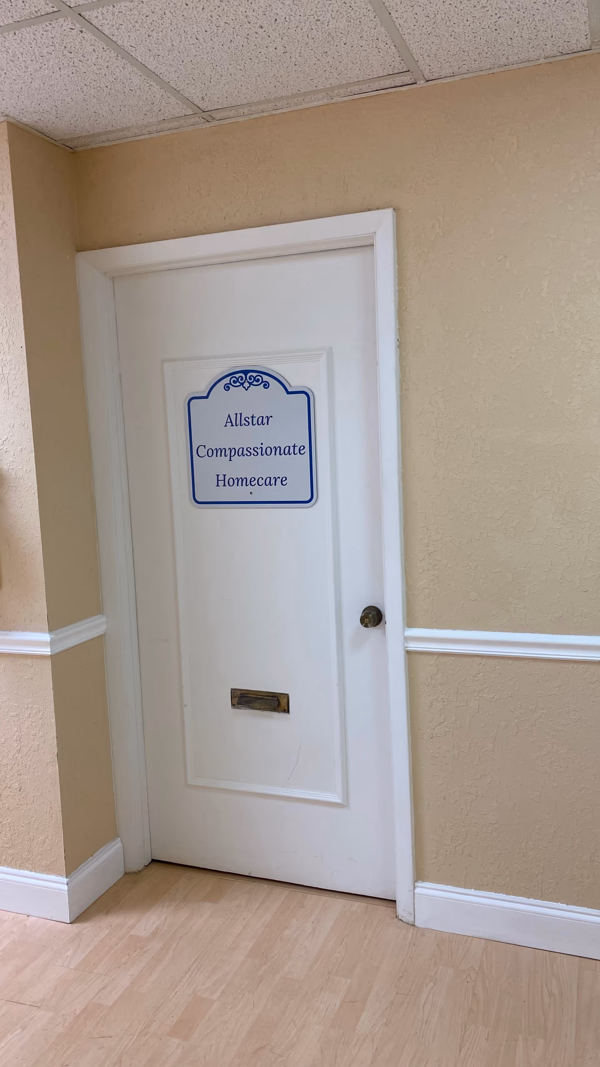 White door with Allstar Compassionate Homecare sign in a beige hallway.