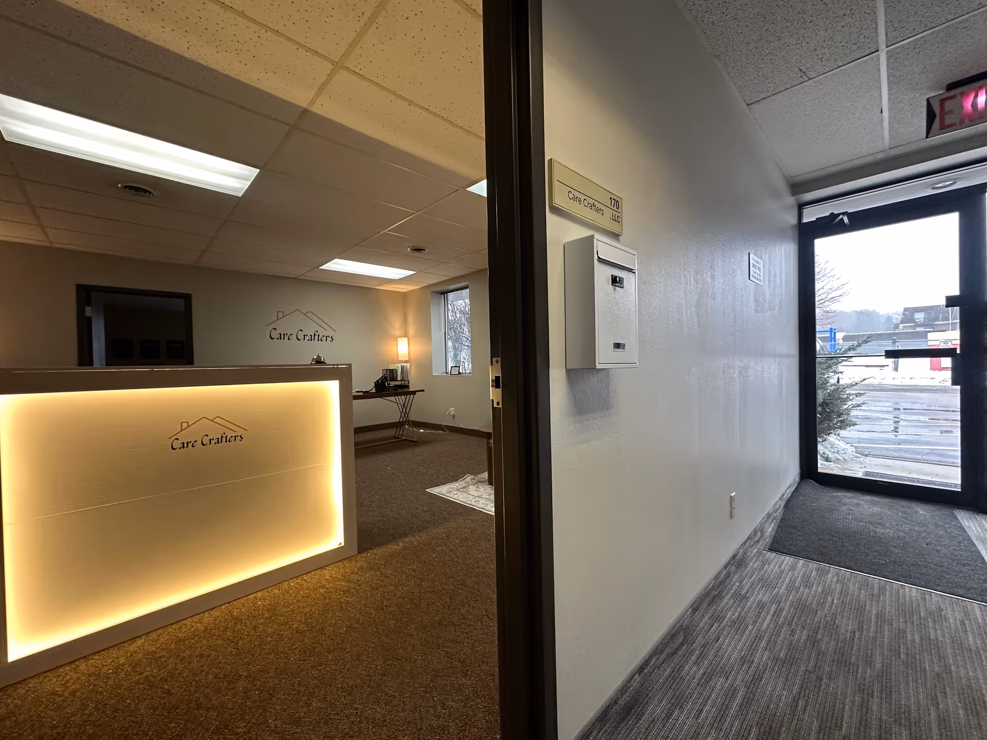 Reception desk with Care Crafters logo in a modern lobby and glass entry