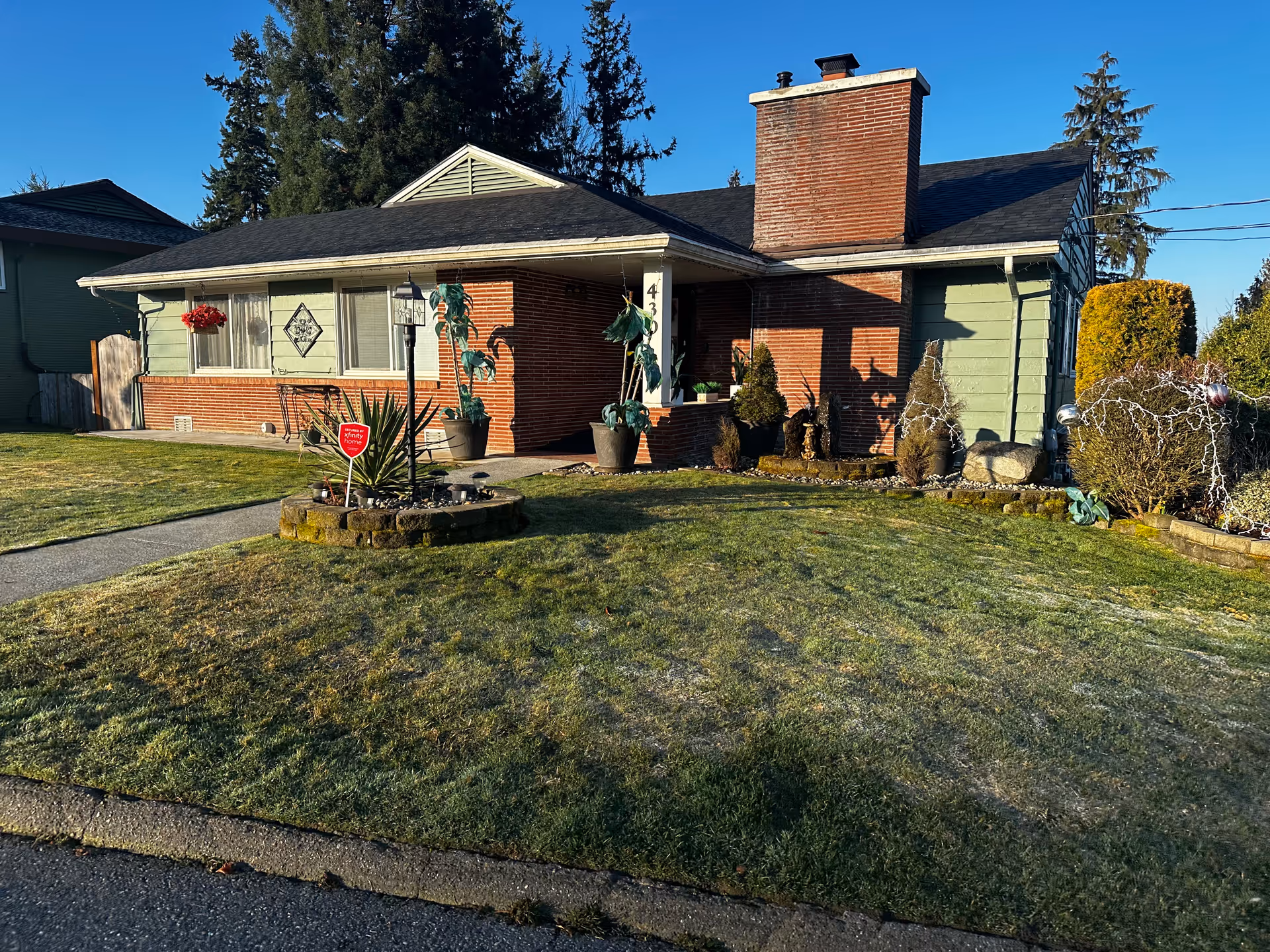 Front view of a single-story care home with a brick chimney and green siding.