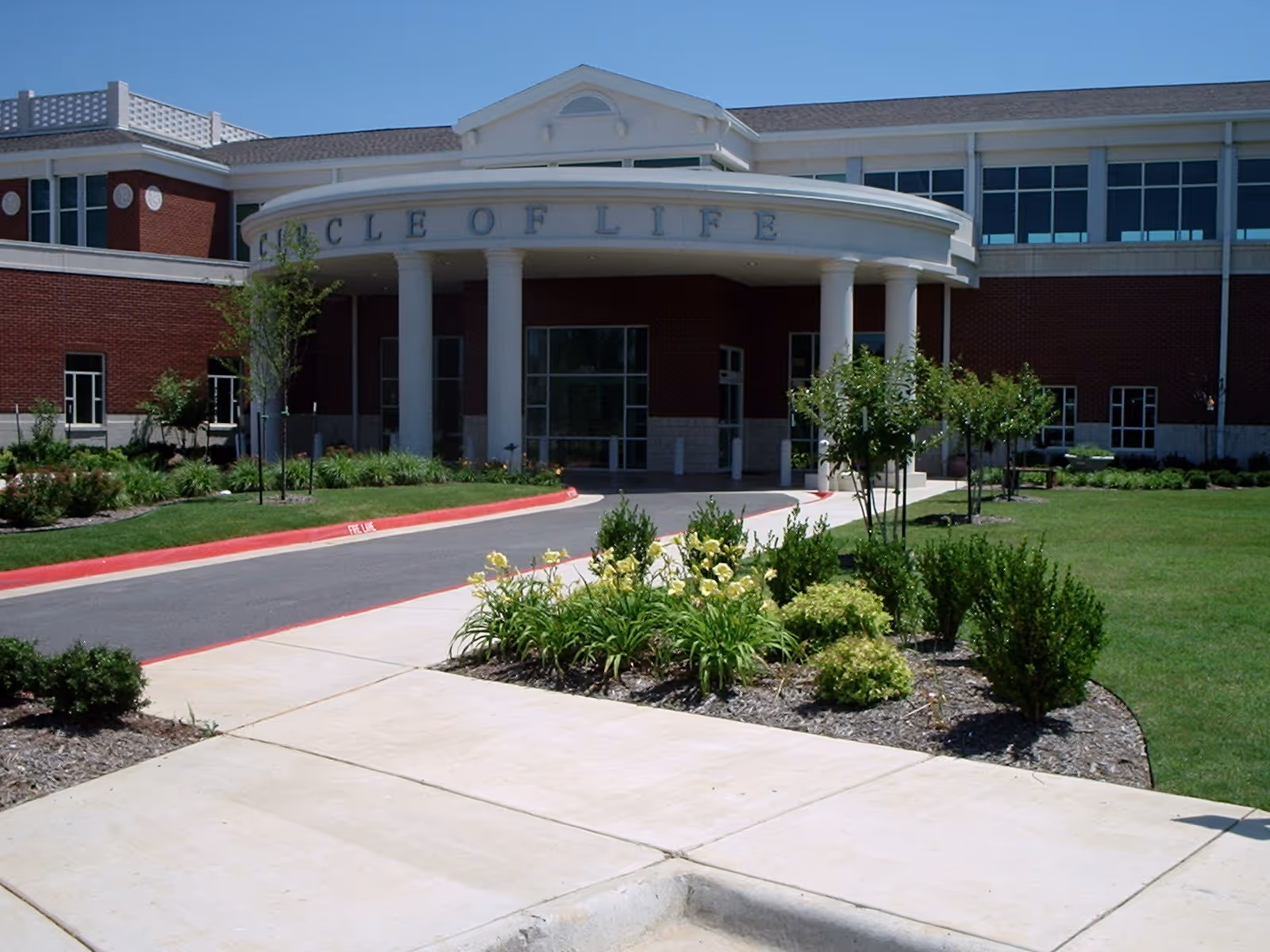 Exterior view of Circle of Life senior living facility entrance with landscaping.