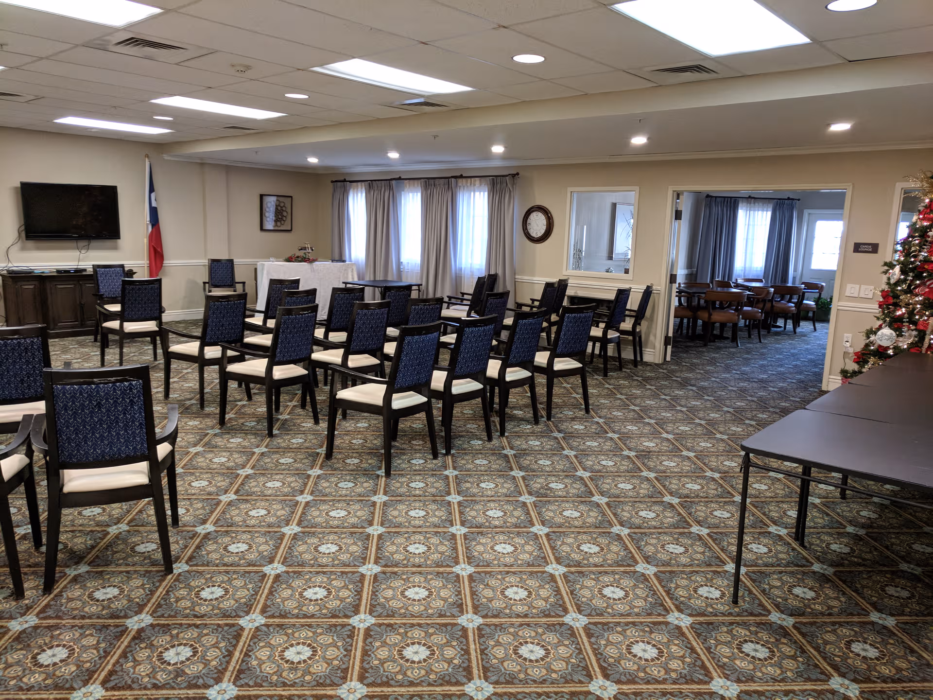 Rows of blue chairs in a meeting room with a Christmas tree and Texas flag.