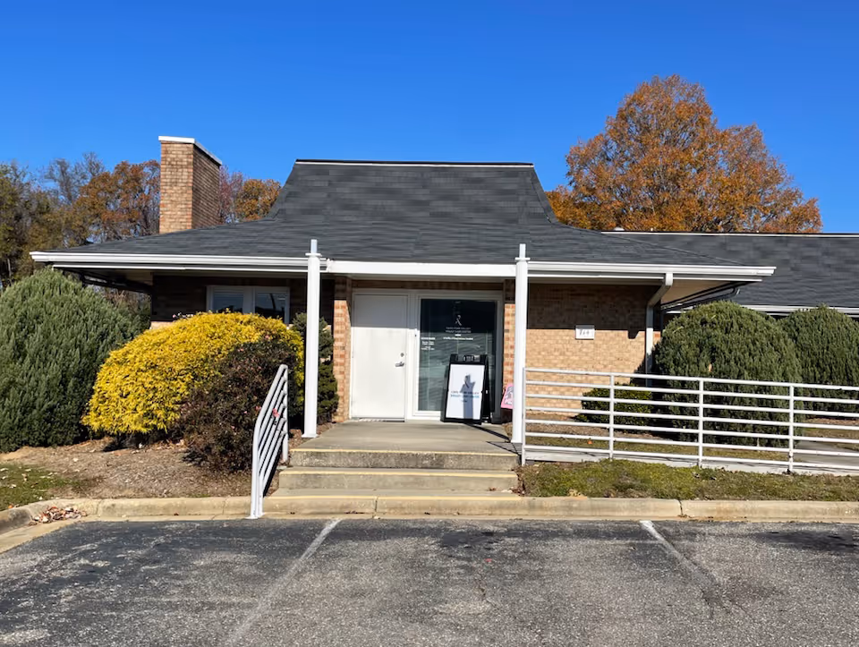 Front view of a single-story brick medical center entrance with ramp and landscaping.