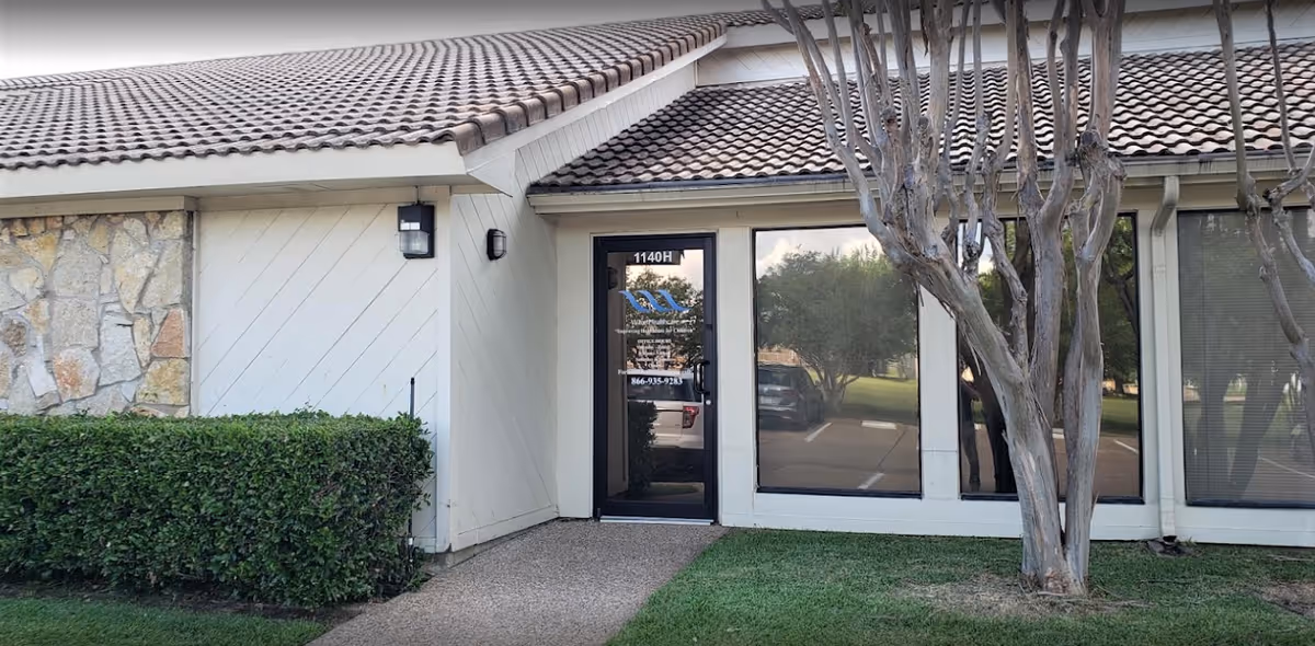Exterior view of Wave Healthcare Arlington entrance with glass door and landscaping.