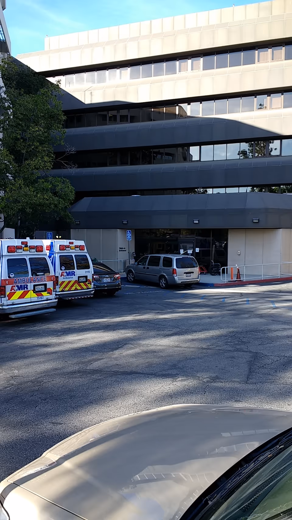 Exterior view of a hospital entrance with ambulances parked outside.