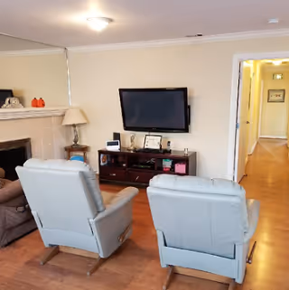 Cozy living area with two light blue recliners and a television on a wooden stand.
