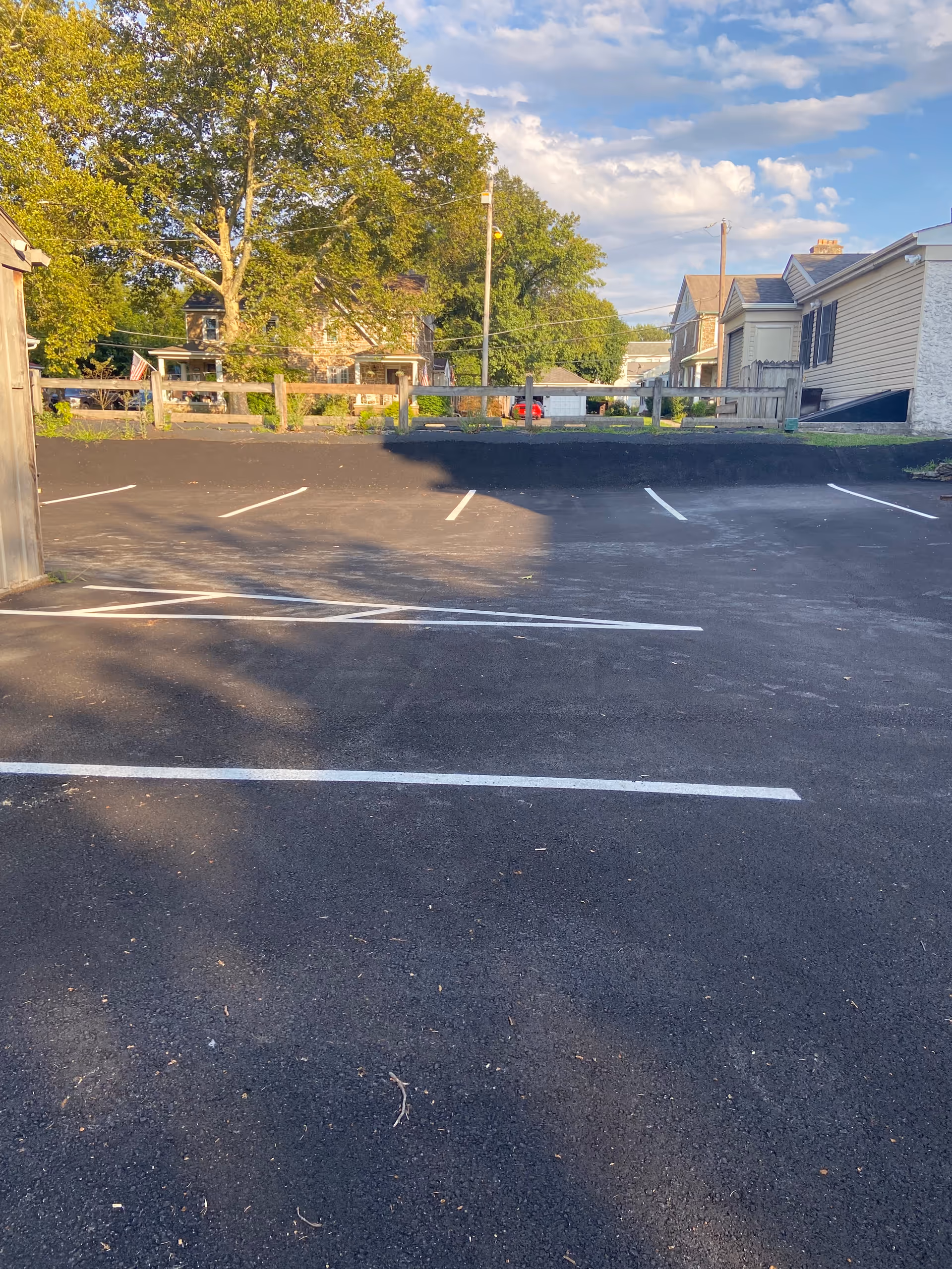 Outdoor parking lot with white lines, a railing, and residential-style buildings in the background.