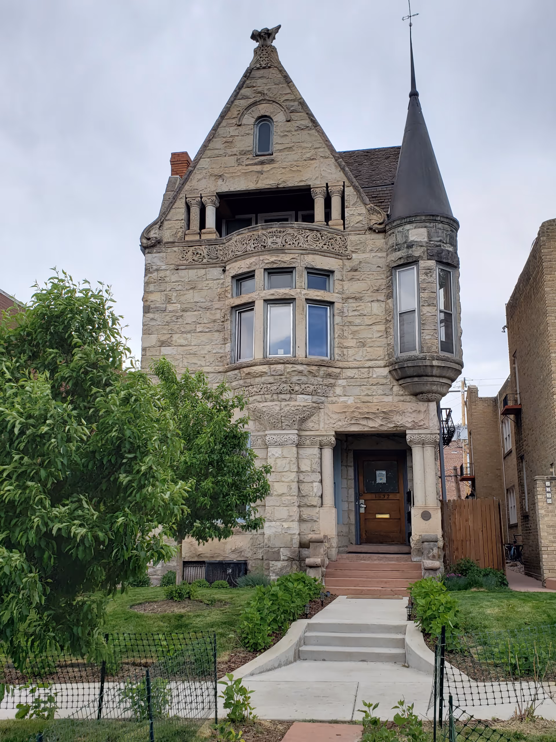 Stone castle-style building facade with turret, arched windows, and front entrance steps.
