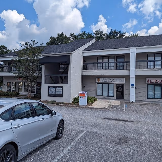 Strip mall exterior with parked car, storefronts, and a FedEx drop box.