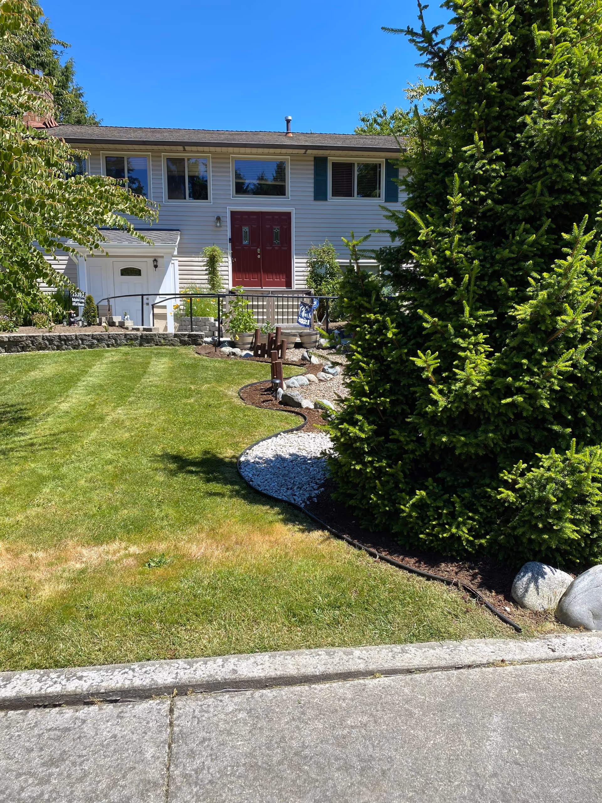 Front exterior of Delightful Living AFH of Edmonds, showing lawn, shrubs, and red entry doors.