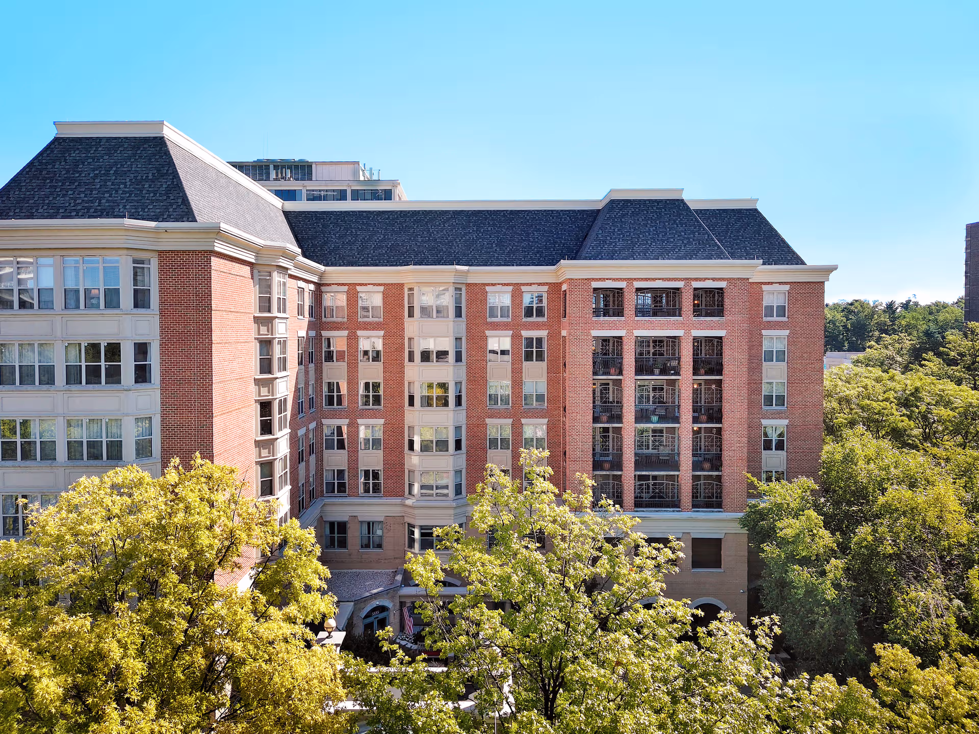 Exterior view of Brighton Gardens of Friendship Heights, a brick senior living building with trees.