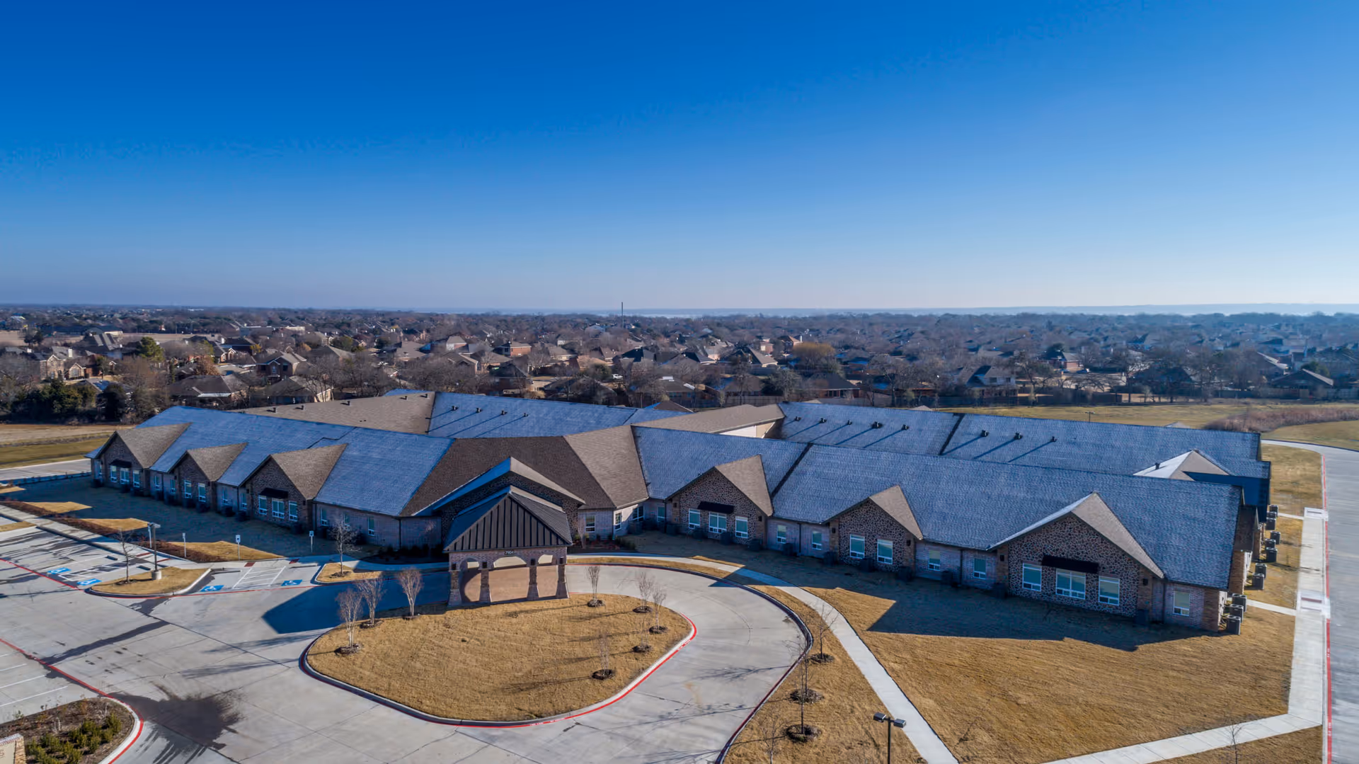 A single-story brick senior living facility with a curved driveway and front entrance.