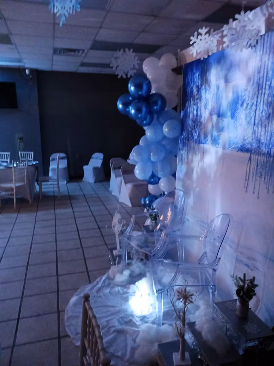 Indoor event space decorated with blue balloons, snowflakes, and an icy backdrop.