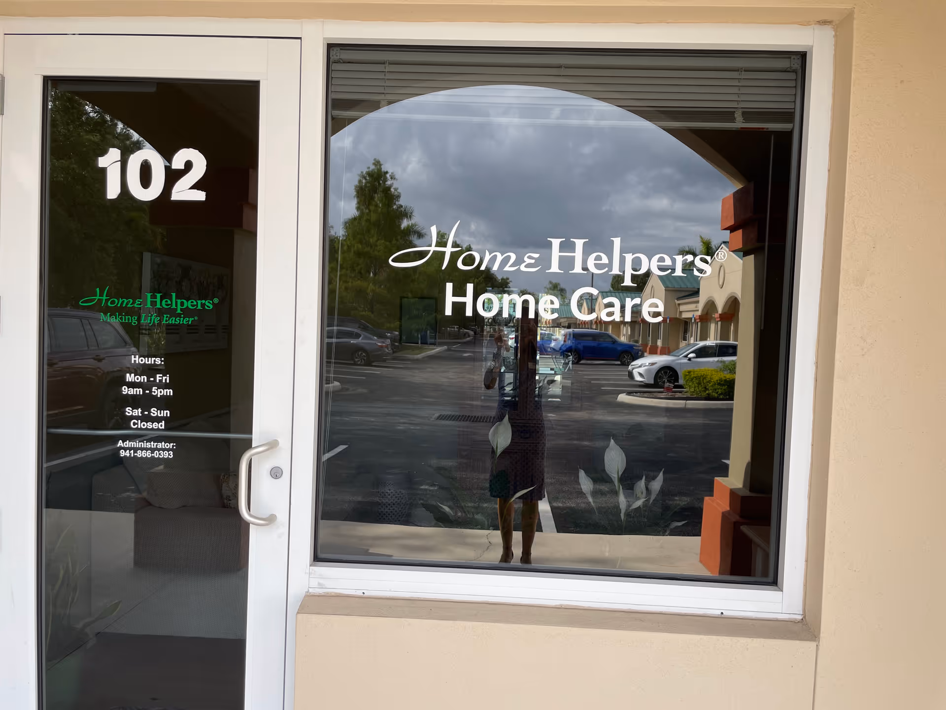 Front entry of Home Helpers Home Care, glass door and window with logo, parking lot reflections.