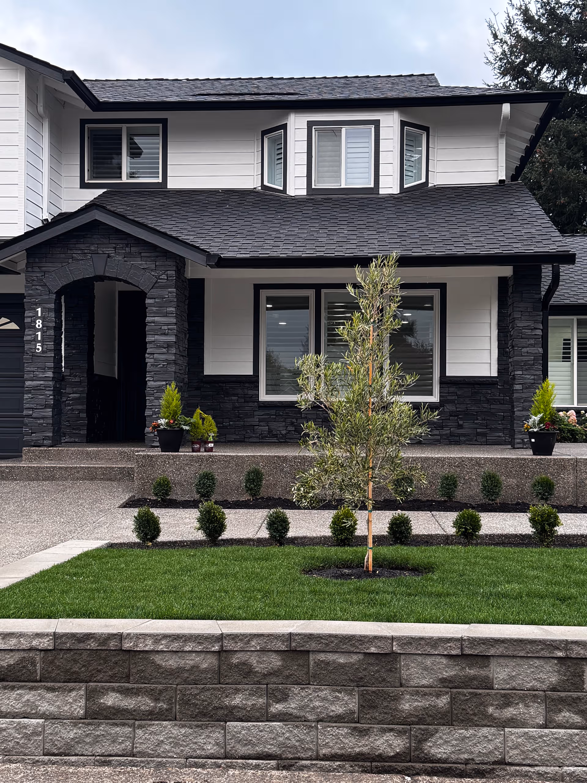 Front exterior of Olive Tree Adult Family Home with white and dark stone facade.