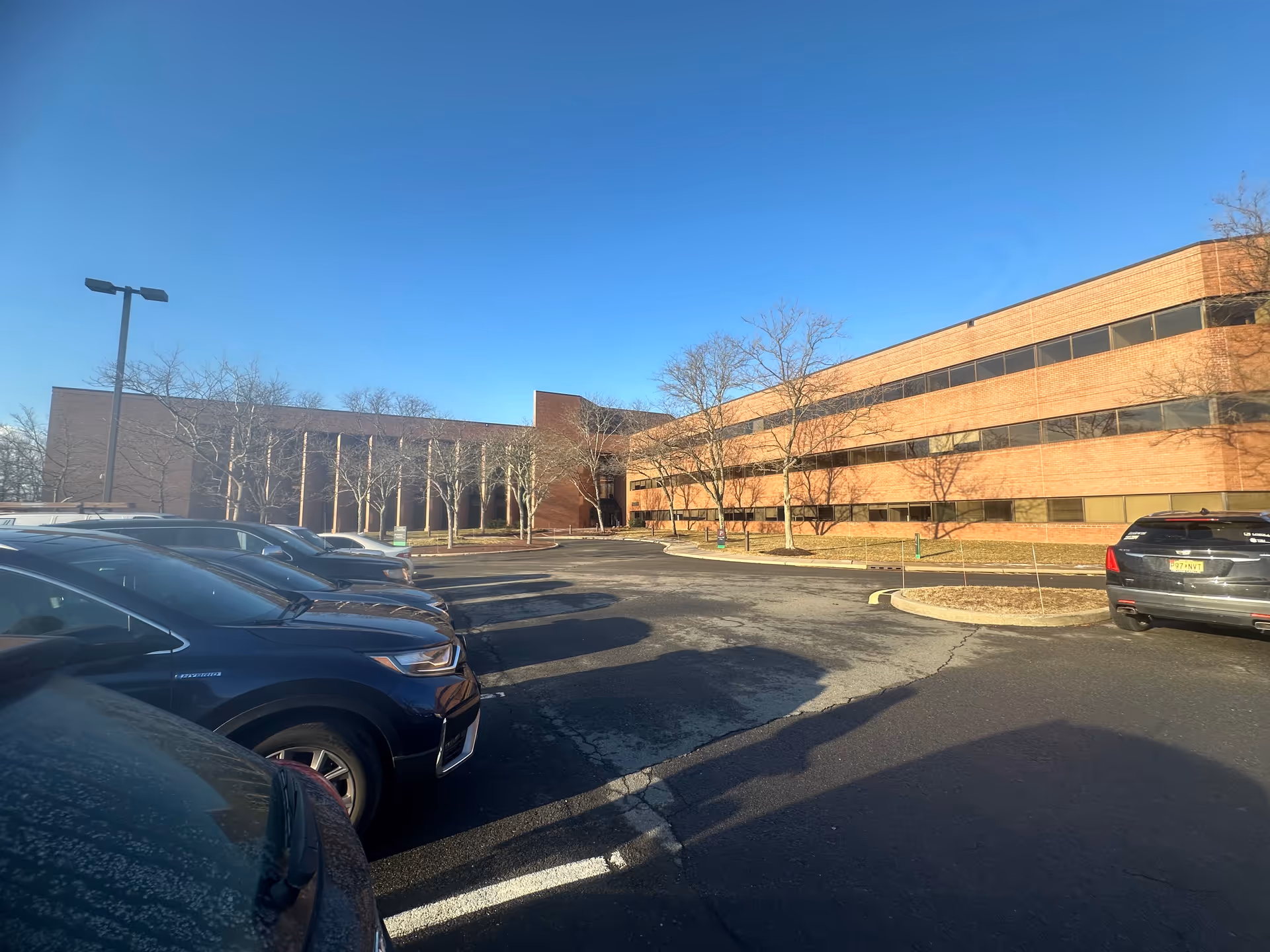 Exterior view of a brick senior living facility with parked cars and blue sky.