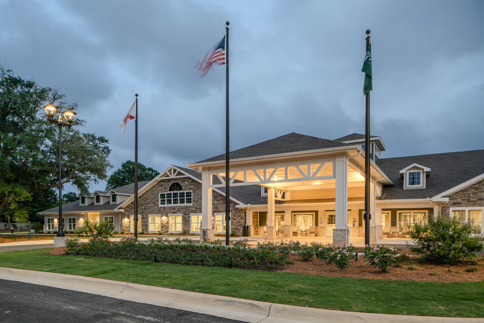 Exterior view of PruittHealth - Pensacola facility with entrance canopy, flags, and landscaped grounds.