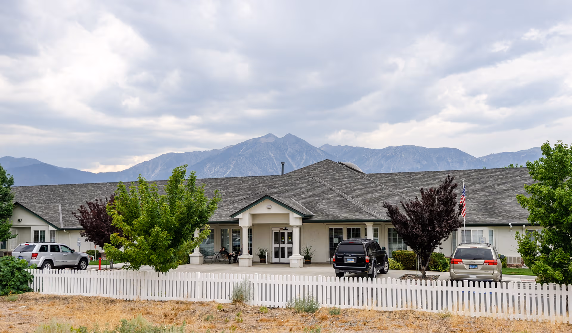 Front exterior of Volante Senior Living of Carson Valley with entrance, parking, and mountains.