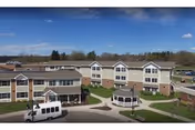 Exterior view of a senior living campus with beige buildings and a curved driveway.