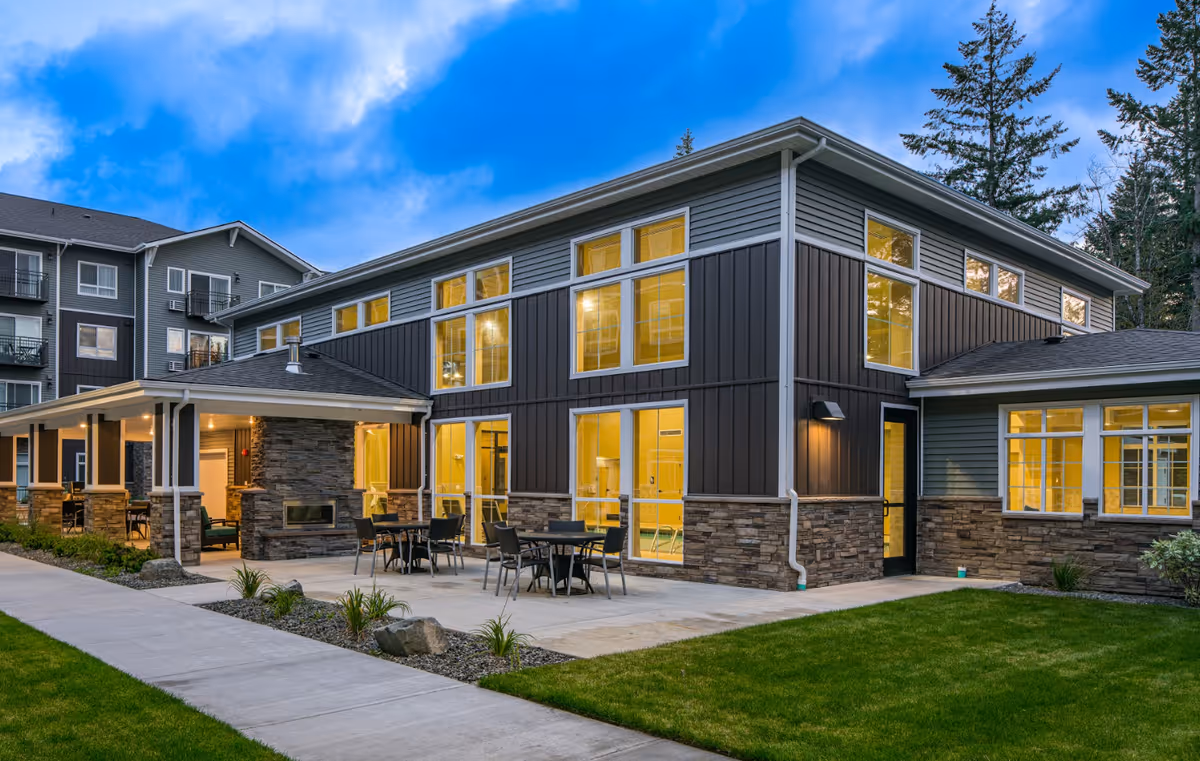 Exterior view of Affinity at Lacey building with outdoor seating patio and warm interior lights.