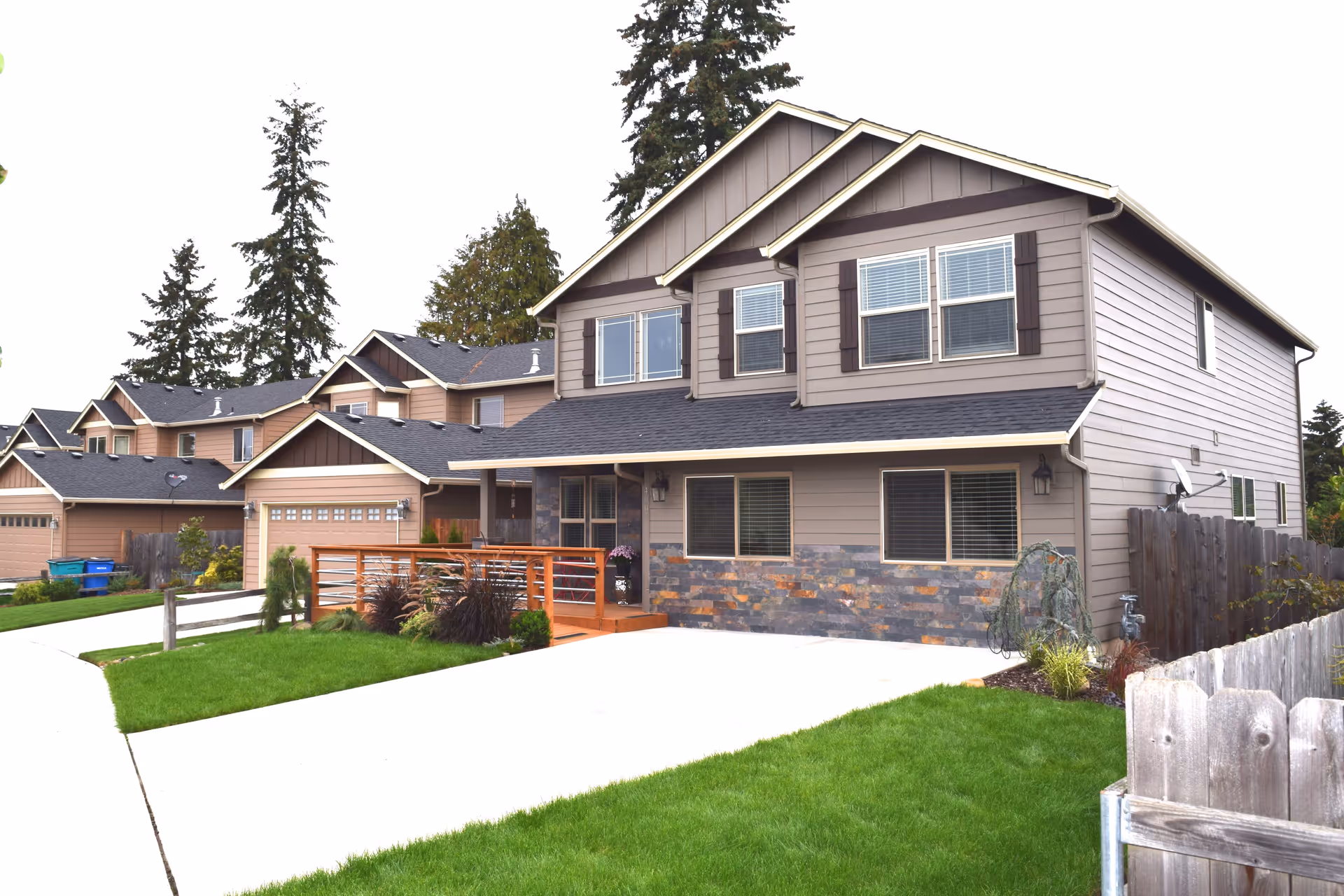 Two-story suburban home front with a driveway, green lawn, and neighboring houses.