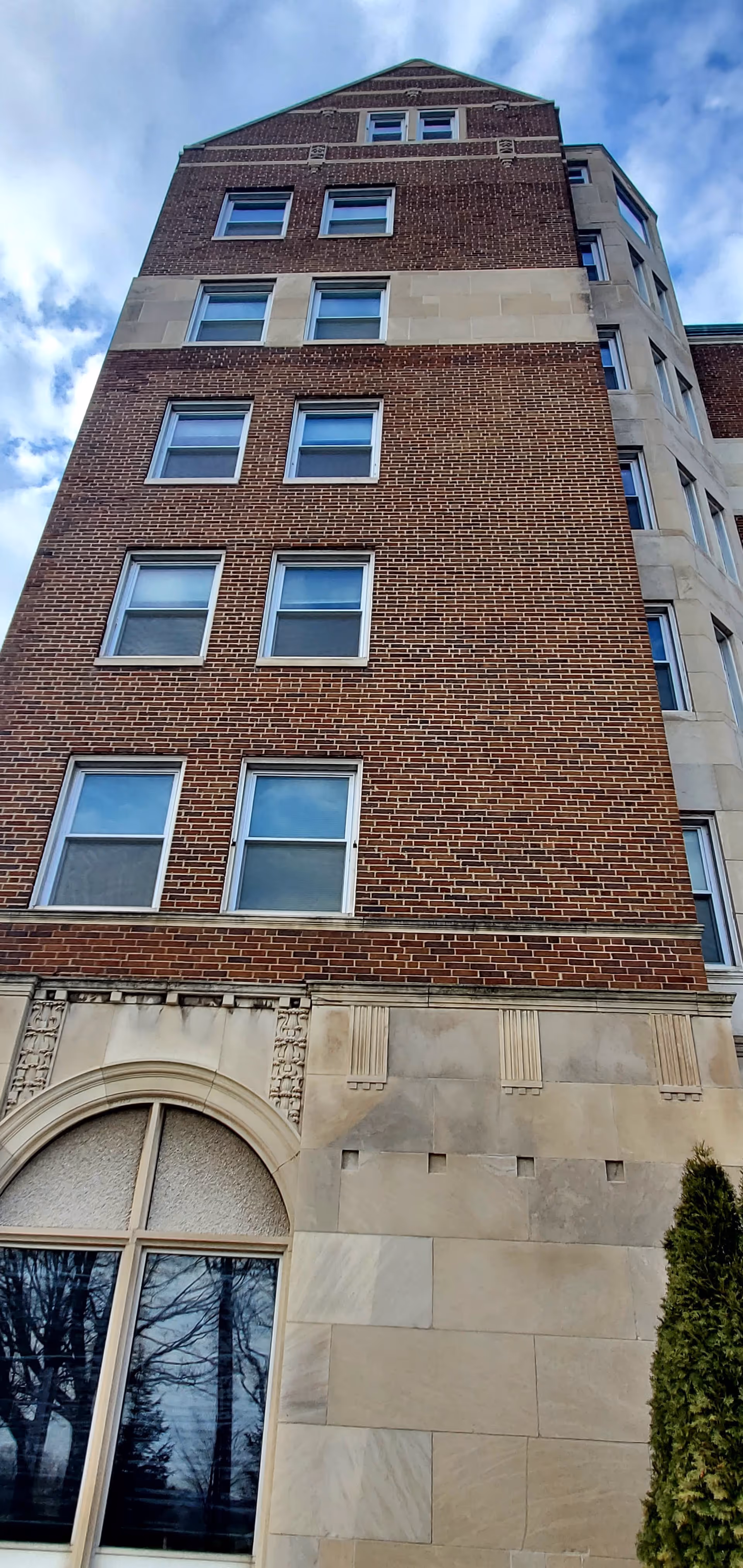 Tall brick senior living tower exterior with many windows and stone base.