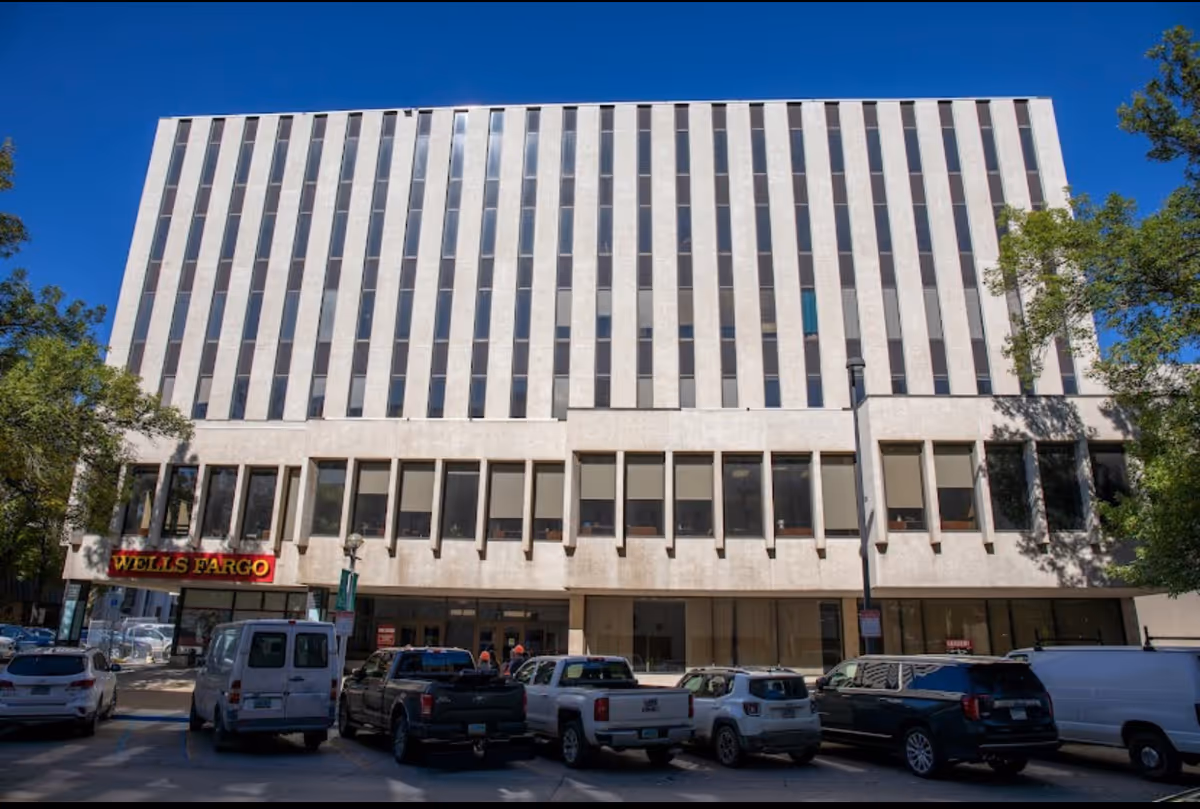 Tall beige office building with Wells Fargo storefront and parked cars along the street.