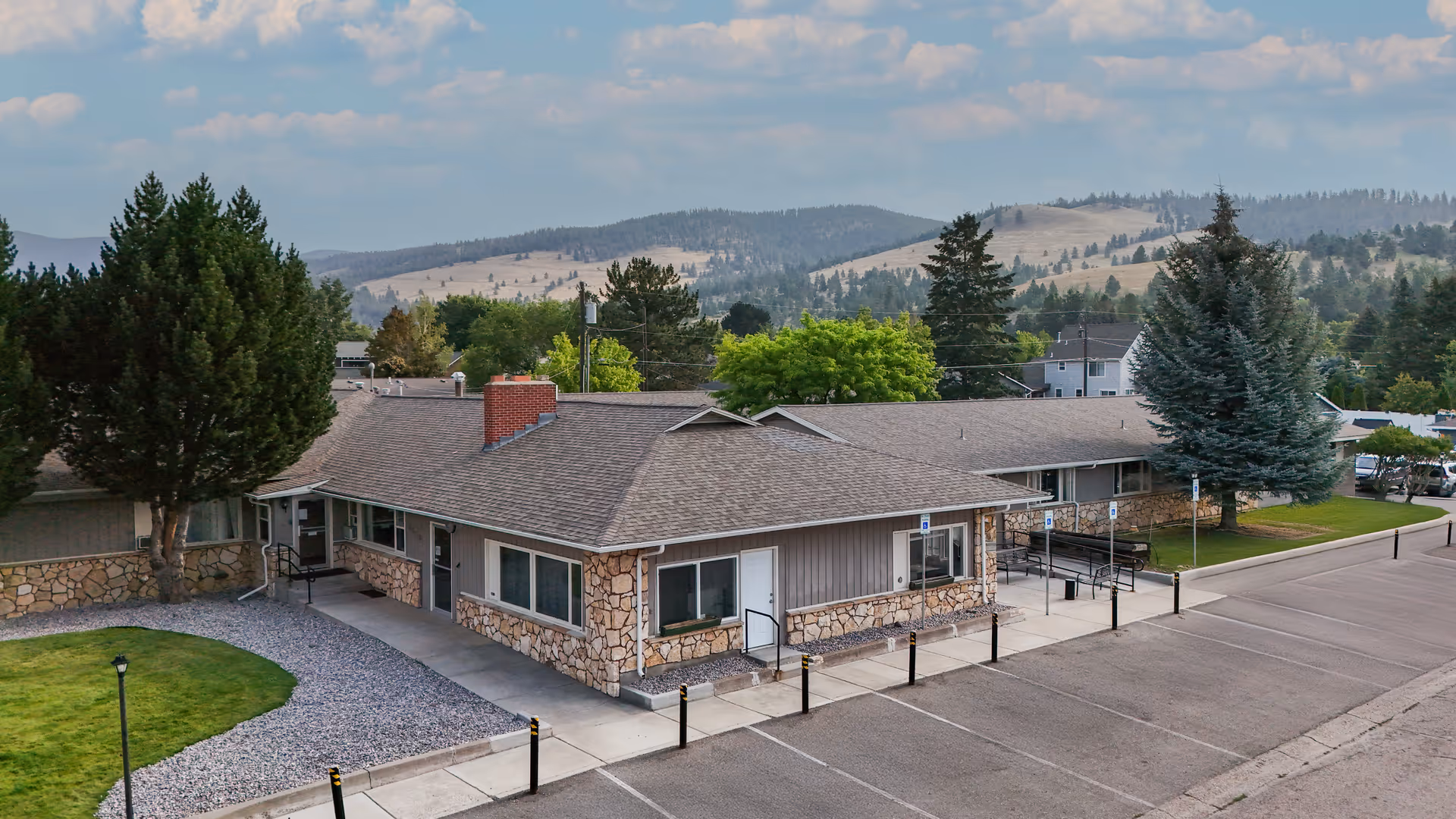 Exterior view of a single-story senior facility with stone accents and parking.
