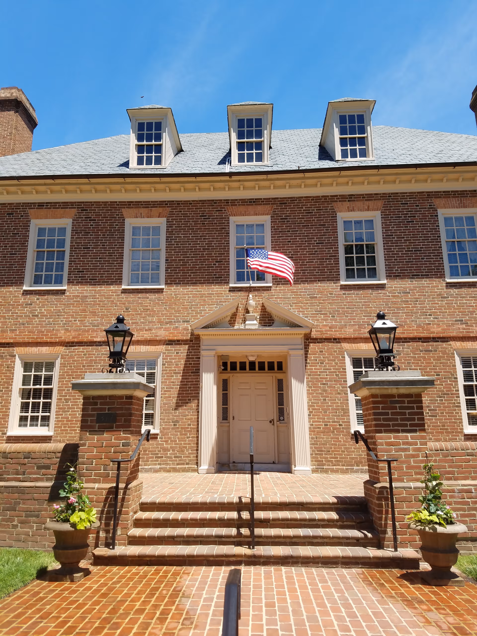 Front exterior of a brick senior living facility with steps, flag, and lanterns.