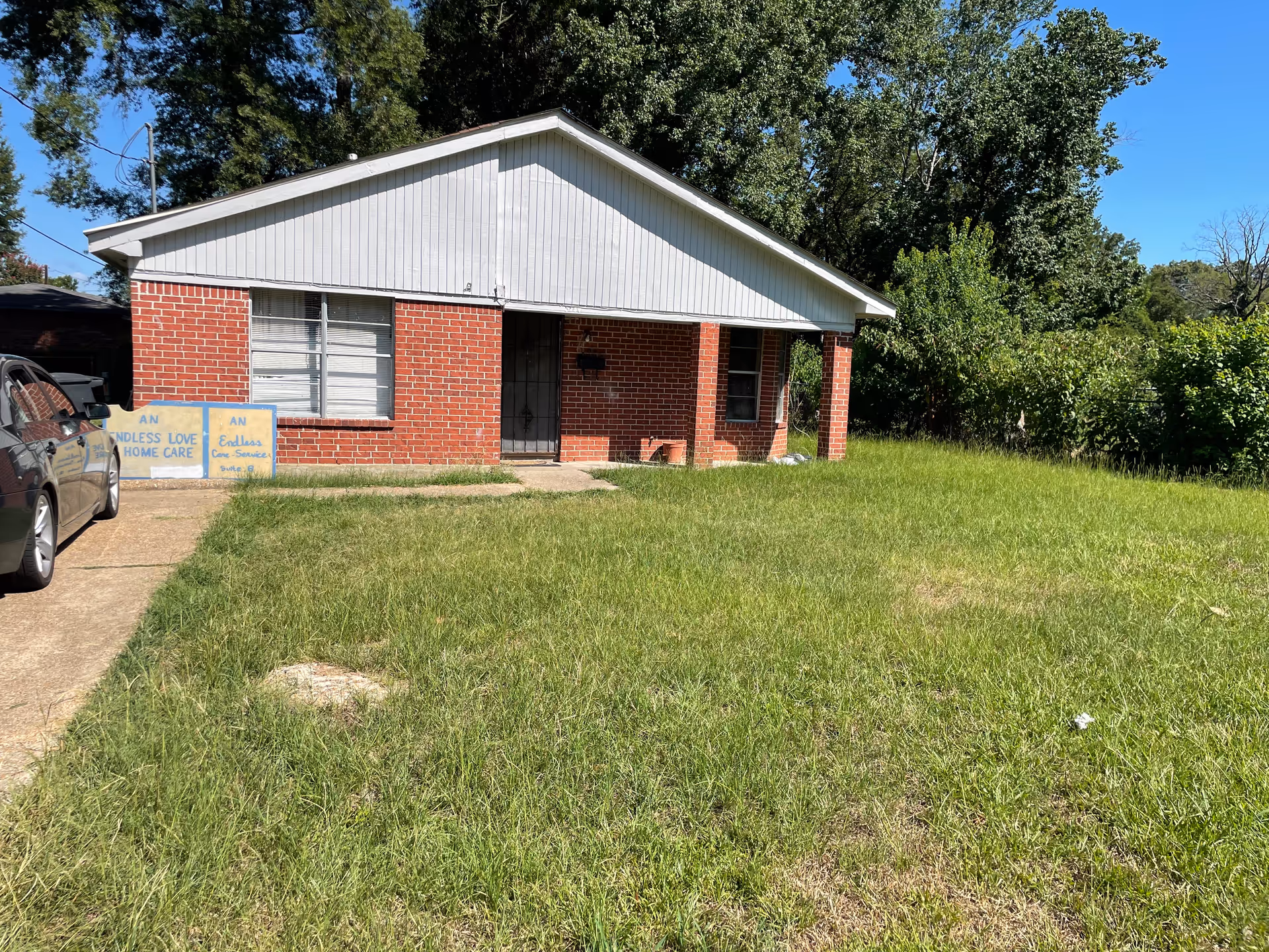 Brick one-story building with white trim, front entrance, yard sign for An Endless Love Home Care.