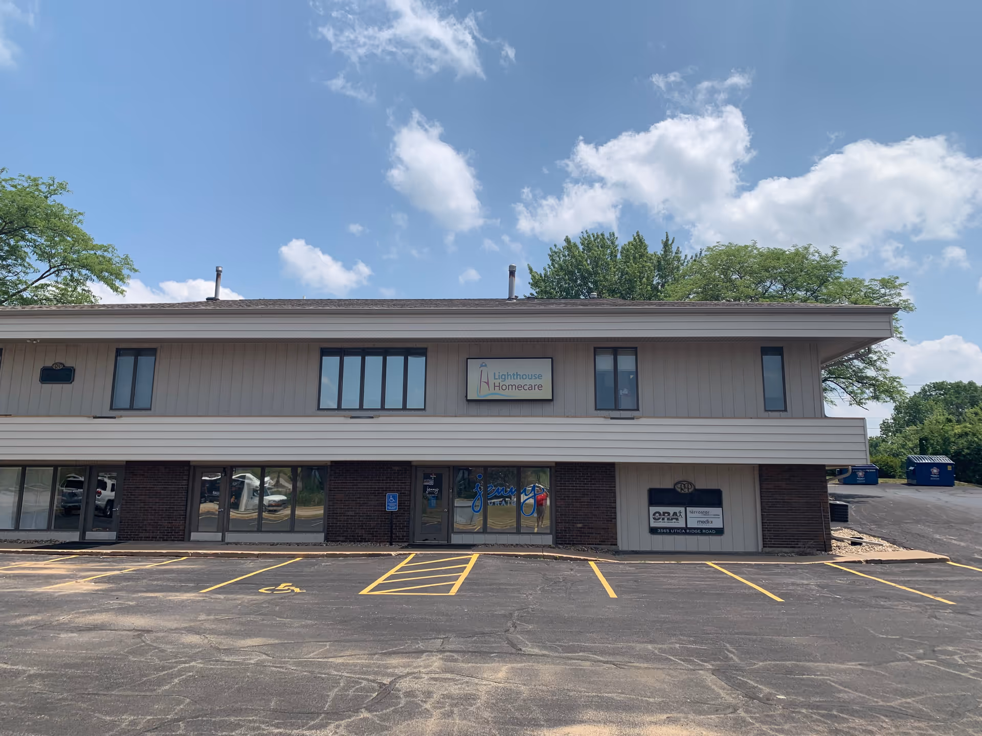 Front exterior of Lighthouse Homecare building with parking lot and blue sky.